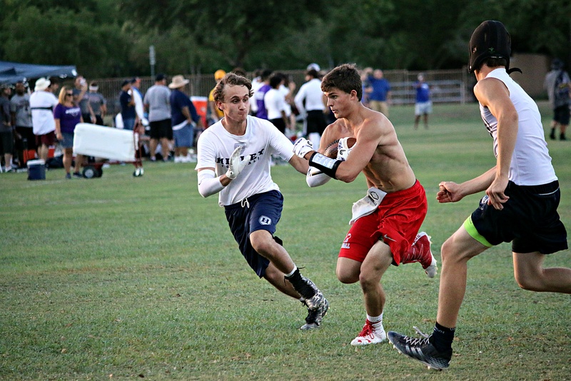 Football player protects a football as other players attempt to take it